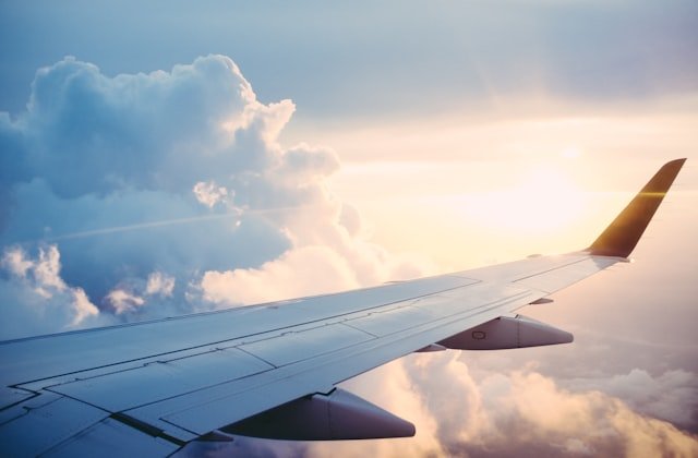 Aircraft wing above golden clouds at sunset